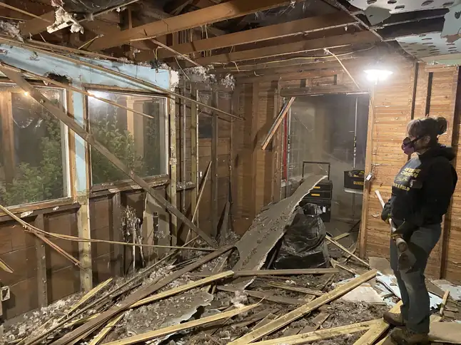 A fire and water tear-out down to the studs, debris on the floor and a worker in a respirator