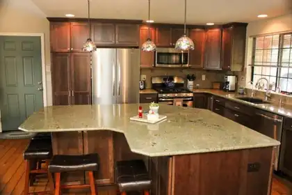 Kitchen with dark wood cabinets and a large granite island with bar stools