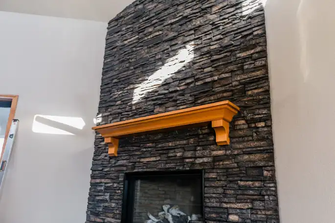 Floor-to-ceiling stacked-stone fireplace with a timber mantel
