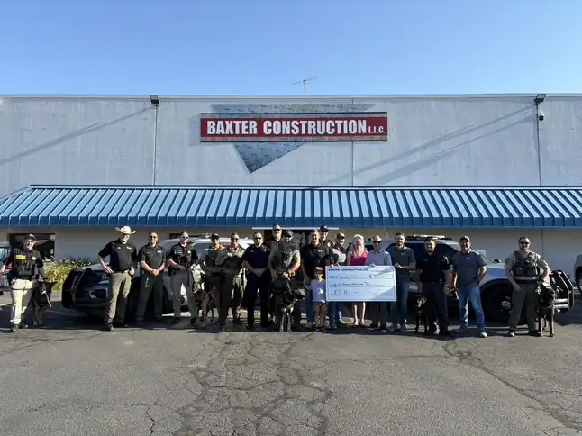 Baxter crew with Yakima County K9 deputies holding a donation check in front of the building